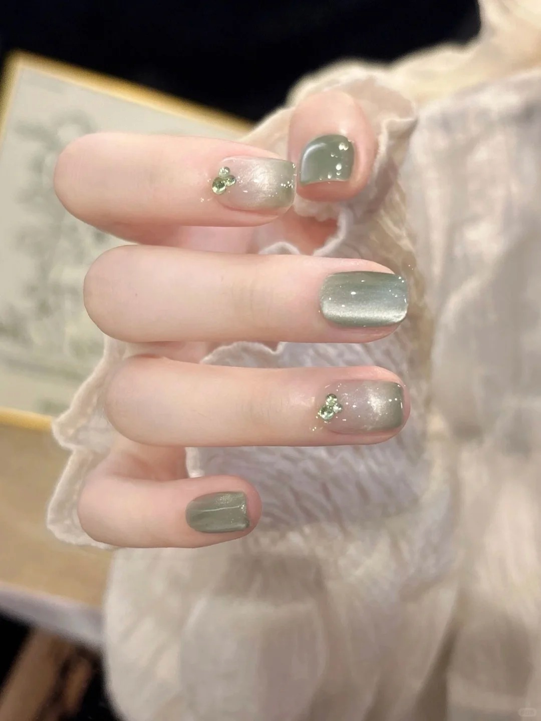 Short square olive green manicure with subtle silver shimmer and crystal accents